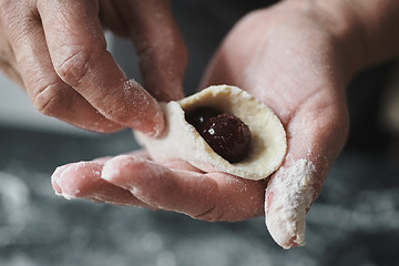 Image showing Woman cook manually sculpts dumplings stuffed with cherries