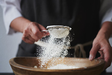 Image showing Female hands sifting flour to bowl.