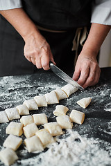 Image showing Women\'s hands cut the dough into pieces with kitchen knife