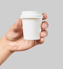 Image showing Mockup of men\'s hand holding white paper espresso cup with white cover