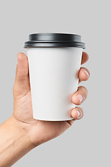 Image showing Mockup of men\'s hand holding white paper mid size cup with black cover