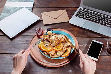 Image showing Laptop and pancakes with juice. Healthy breakfast