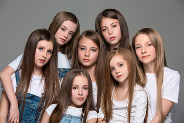 Image showing Three happy girls sitting together and looking at camera. Isolated over white.