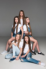 Image showing Three happy girls sitting together and looking at camera. Isolated over white.