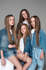 Image showing Three happy girls sitting together and looking at camera. Isolated over white.