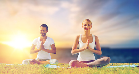 Image showing happy couple making yoga and meditating outdoors