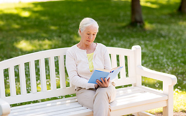 Image showing senior woman reading book at summer park