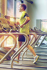 Image showing man with smartphone exercising on treadmill in gym