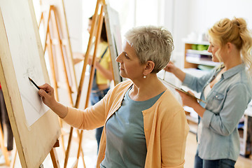 Image showing senior woman drawing on easel at art school studio