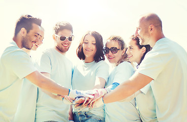 Image showing group of volunteers putting hands on top in park