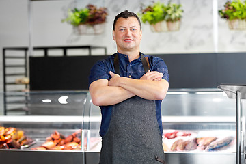 Image showing male seller with seafood at fish shop fridge