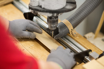 Image showing carpenter with drill press and board at workshop