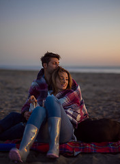 Image showing Loving Young Couple Sitting On The Beach beside Campfire drinkin