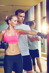 Image showing smiling woman with personal trainer boxing in gym