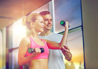 Image showing smiling young woman with personal trainer in gym