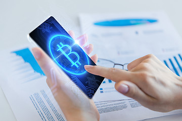 Image showing close up of hand with bitcoin on smartphone screen