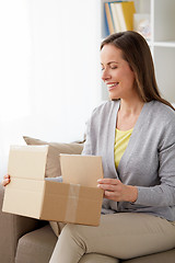 Image showing smiling woman opening parcel box at home