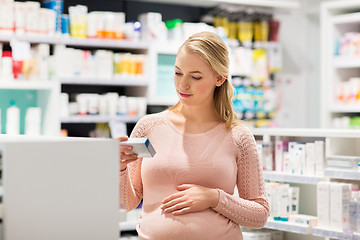 Image showing happy pregnant woman with medication at pharmacy