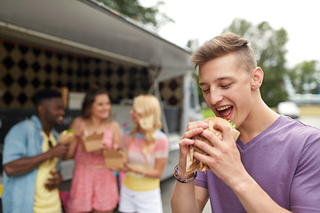 Image showing happy man with hamburger and friends at food truck