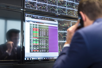 Image showing Stock trader looking at market data on computer screens.