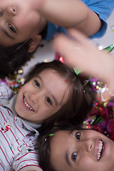 Image showing kids  blowing confetti while lying on the floor