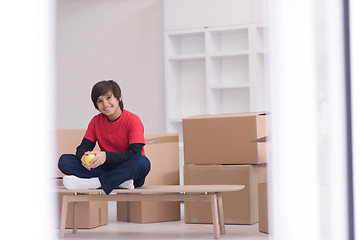 Image showing boy sitting on the table with cardboard boxes around him