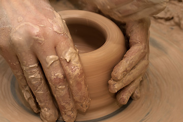 Image showing Women hands in process of making clay bowl on pottery wheel