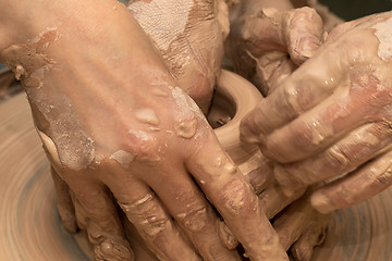 Image showing Beginner and teacher in process of making clay bowl on pottery w