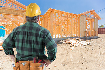 Image showing Contractor Standing Outside Construction Framing of New House.