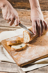 Image showing Whole grain bread put on kitchen wood plate with a chef holding gold knife for cut.