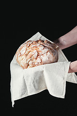 Image showing Closeup of male hands put fresh bread on black background with copy space for your text