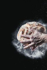 Image showing Closeup of male hands put fresh bread on black background with copy space for your text