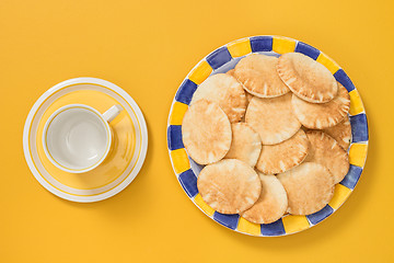 Image showing Teacup and plate with pita bread on yellow background