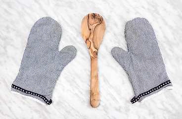 Image showing Wooden spoon and striped kitchen gloves