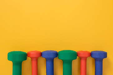 Image showing Multicolored dumbbells on bright yellow background