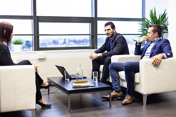 Image showing Businessmen interviewing female candidate for job in modern corporate office.