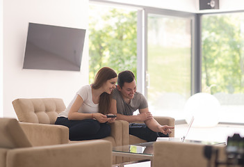 Image showing couple relaxing at  home with tablet and laptop computers