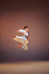 Image showing Young boy training karate on blue background