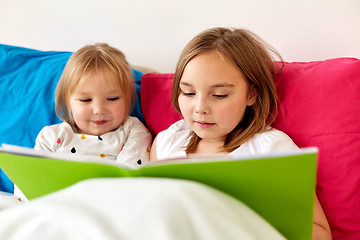 Image showing little girls or sisters reading book in bed