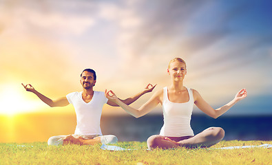 Image showing happy couple making yoga and meditating outdoors