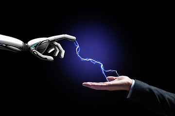 Image showing robot and human hand connected by lightning