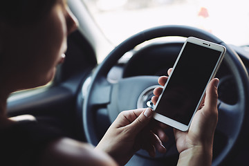 Image showing Woman looking at the screen of the smartphone in the car