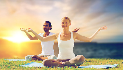 Image showing happy couple making yoga and meditating outdoors