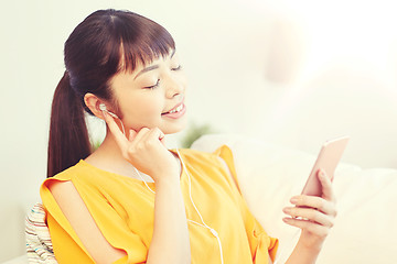 Image showing happy asian woman with smartphone and earphones