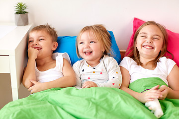 Image showing happy little kids having fun in bed at home