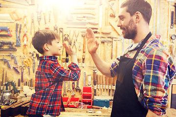 Image showing father and little son making high five at workshop