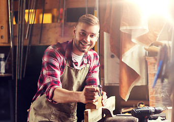 Image showing carpenter working with plane and wood at workshop