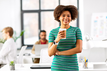 Image showing smiling african woman drinking coffee at office