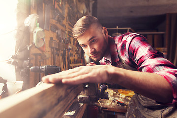 Image showing carpenter working with wood plank at workshop