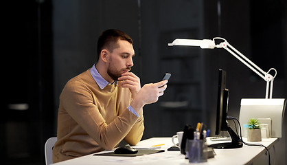 Image showing man with smartphone working late at night office